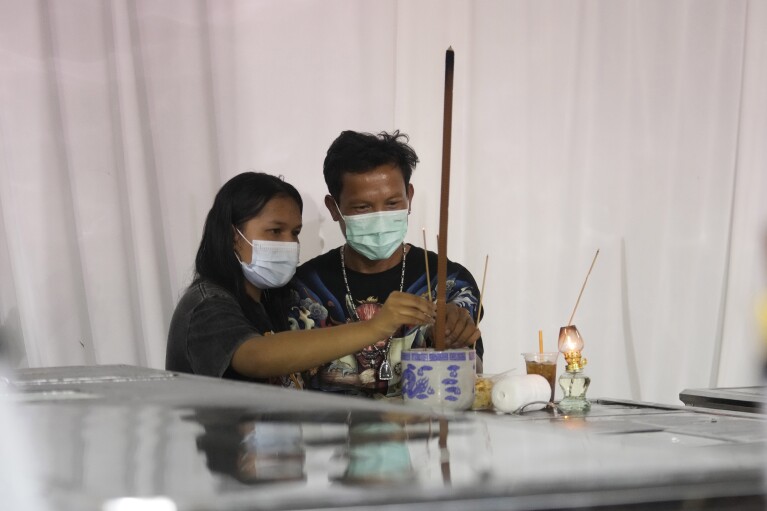 在一个小镇为泰国巴士大火的受害者举行的葬礼上,人们共同缅怀和祈祷